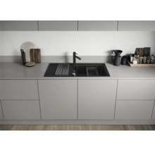 Keukenscène met spoelbak, kraan en keukengerei op een aanrecht.