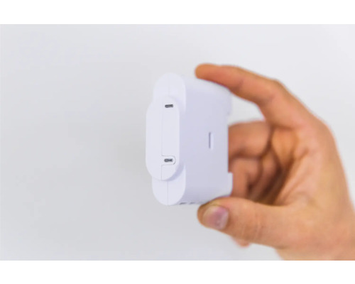 Hand houdt een witte Shelly-energiesensor vast