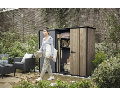 Tuinscène met vrouw voor gereedschapsschuur met tuingereedschap en tuinmeubelen