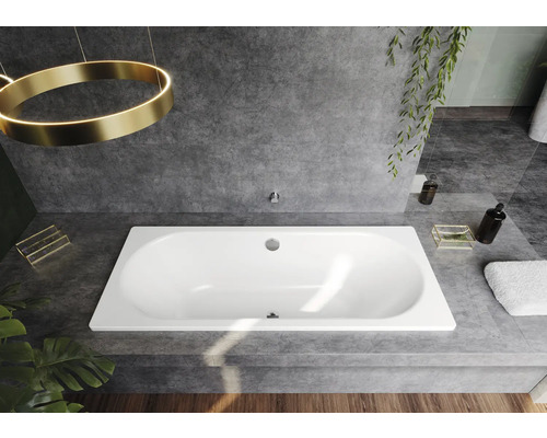 Inbouwbad in een badkamer met grijze tegels en decoratieve elementen.