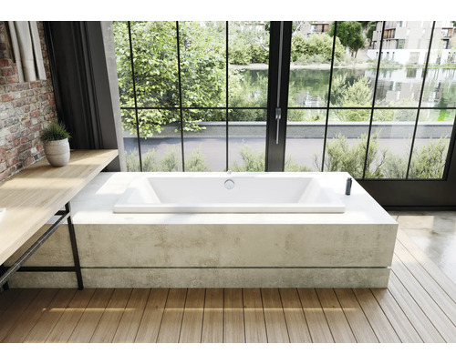 Rechthoekig bad in een lichte badkamer met houten vloer en groot raam met uitzicht op groen.