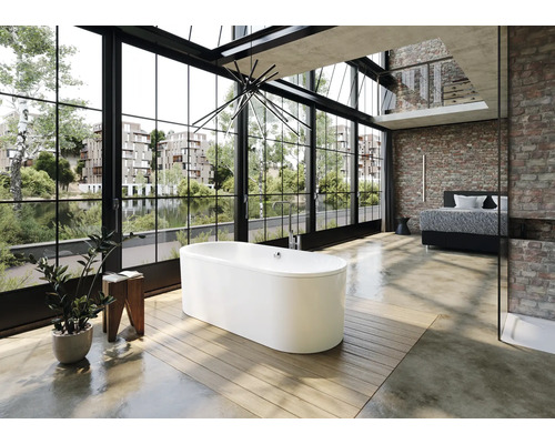 Vrijstaand bad in een heldere badkamer met groot raam en bakstenen muur.