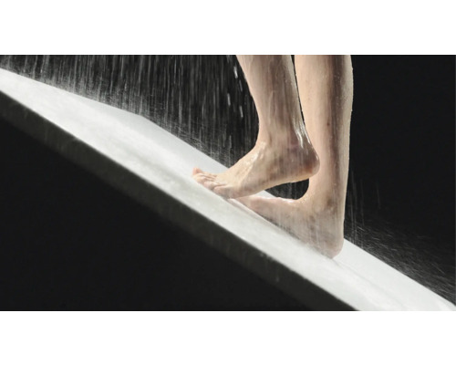 Persoon staat onder de douche in een douchebak.