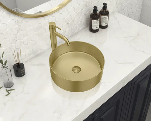 Op een wastafel bevindt zich een goudkleurige opzetwastafel met kraan