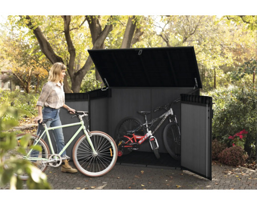 Vrouw schuift fiets in gereedschapsschuur met fietsen in de tuin