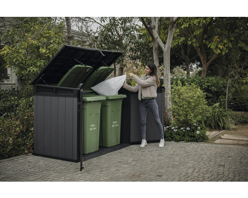 Afvalcontainerbox met vrouw die er een vuilniszak in gooit, in de tuin