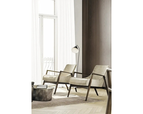 Twee fauteuils met houten frame en een staande lamp in een heldere woonkamer.