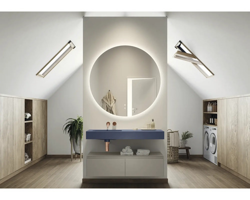 Lichte zolderbadkamer met ronde spiegel met verlichting, wastafel, wasmachine en inbouwkasten