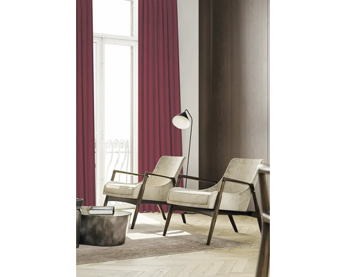 Woonkamer met twee fauteuils, staande lamp en bordeauxrode gordijnen
