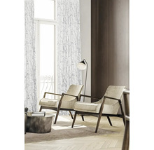 Woonkamer met twee fauteuils, een staande lamp en gordijnen met een motief