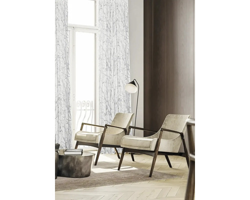 Woonkamer met twee fauteuils, een staande lamp en gordijnen met een motief