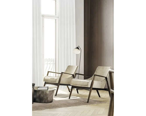 Woonkamer met twee fauteuils, een vloerlamp en een tapijt op een parketvloer