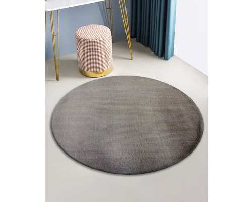 Grijs rond vloerkleed in een kamer met kruk en tafel