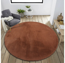 Rond imitatievacht tapijt in een heldere, moderne kamer met een stoel en bijzettafels.