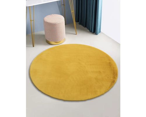 Geel rond tapijt in de kamer met tafel en kruk