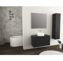 Moderne badkamer met wastafel, spiegel, hoge kast en vrijstaand bad tegen een muur met bladmotief
