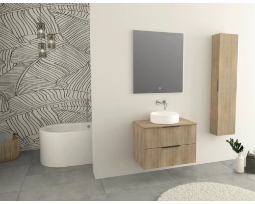 Badkamer met bad, wastafel, spiegel en hangkast in lichte houtdecoratie voor een behang met bladmotief.