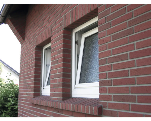 Buitenkant van een bakstenen huis met twee ramen