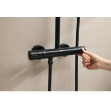 Zwarte douchethermostaat met bediening door een hand voor betegelde muur