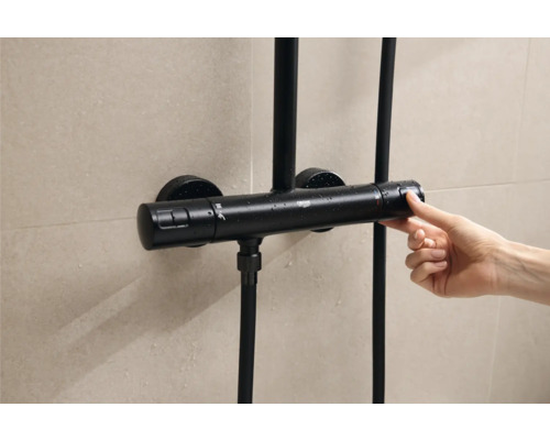 Zwarte douchethermostaat met bediening door een hand voor betegelde muur