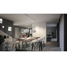 Lichte eetkamer met houten tafel, stoelen en moderne verlichting.