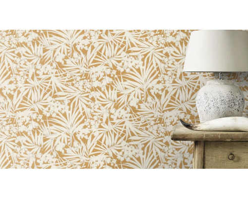 Close-up van een muur met botanisch behang, die een lamp en een houten meubelstuk gedeeltelijk verbergt.