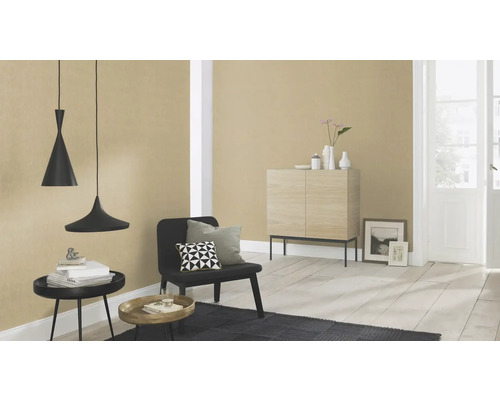 Woonkamer met hanglampen, stoel, vloerkleed en dressoir tegen een behangen muur