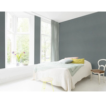 Lichte slaapkamer met bed, stoel en grijze muur