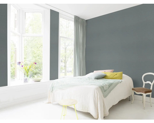 Lichte slaapkamer met bed, stoel en grijze muur