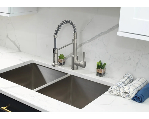 Roestvrijstalen gootsteen met mengkraan en theedoeken op een marmeren aanrecht.