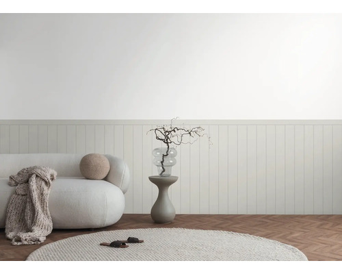 Licht interieur met bank, bijzettafel en decoratieve elementen tegen een lambrisering.