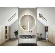 Lichte badkamer op zolder met wastafel, ronde spiegel met verlichting, dakramen en wasmachine.