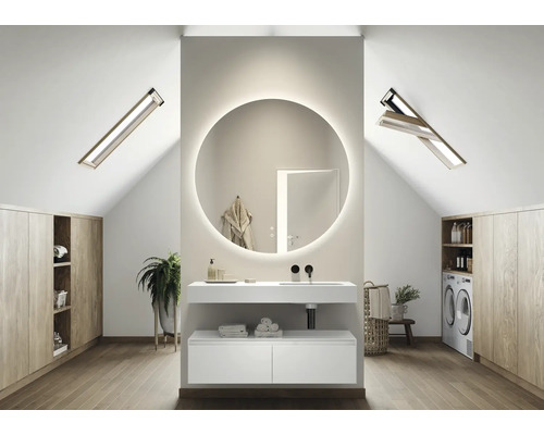 Lichte badkamer op zolder met wastafel, ronde spiegel met verlichting, dakramen en wasmachine.