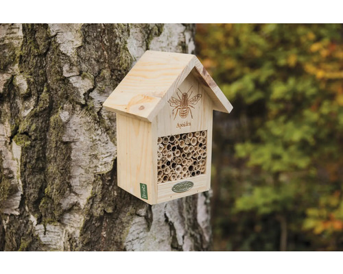 Houten bijenhotel aan een boomstam met buizen als nestplaats