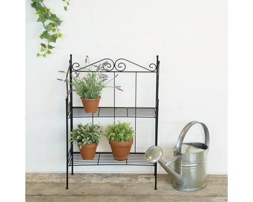 Decoratieve metalen plantentrap met drie niveaus, beplant met kruiden en bloemen, inclusief een gieter.