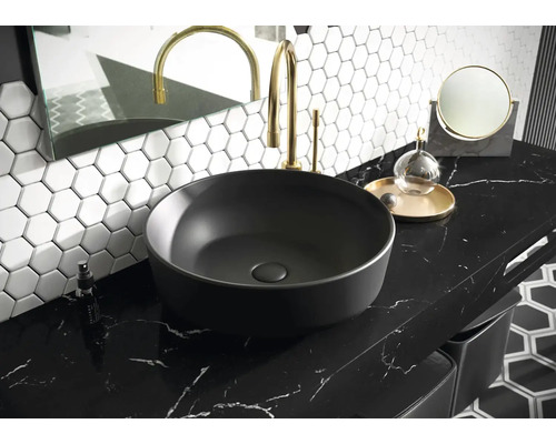 Wastafel op aanrecht in badkamer met kraan, spiegel en zeshoekige tegels