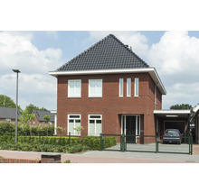Vrijstaand huis met bakstenen gevel, dakpannen en carport