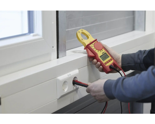 Elektricien meet de spanning op een stopcontact met een stroommeter