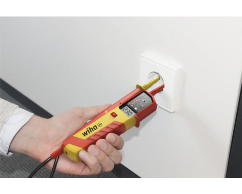 Een hand test een stopcontact met een tweepolige spanningstester. Wiha logo.