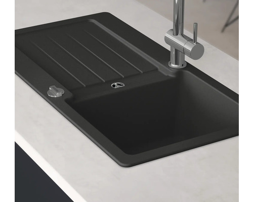 Zwarte spoelbak met afdruiprek en kraan op een aanrecht