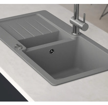 Grijze aanrechtspoelbak met afdruiprek en kraan op een aanrecht.