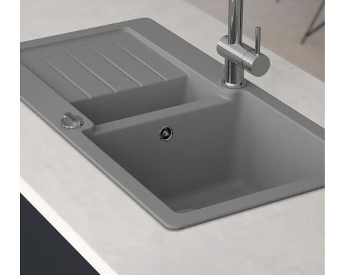 Grijze aanrechtspoelbak met afdruiprek en kraan op een aanrecht.