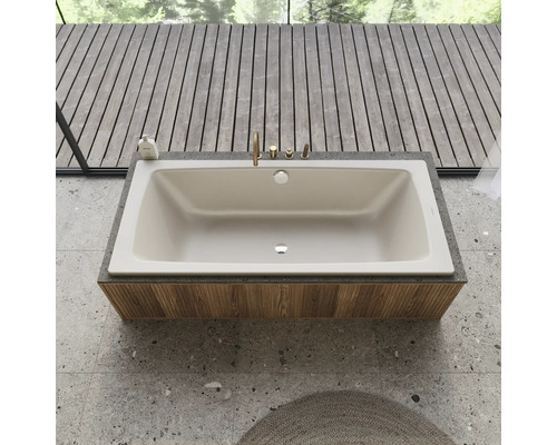 Ingebouwde badkuip met kraan op een houten bekleding in een badkamer