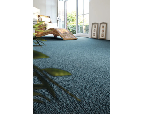 Blauwe vloerbedekking in een lichte kamer met rotan meubels en kamerplant