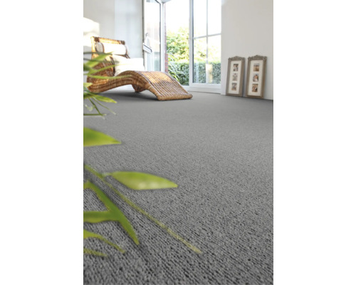 Woonkamer met grijs tapijt, rotan ligstoel en open deur