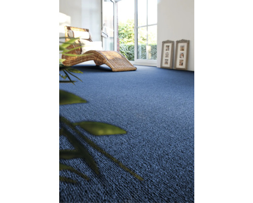 Woonkamer met blauwe vloerbedekking en rotan ligstoel