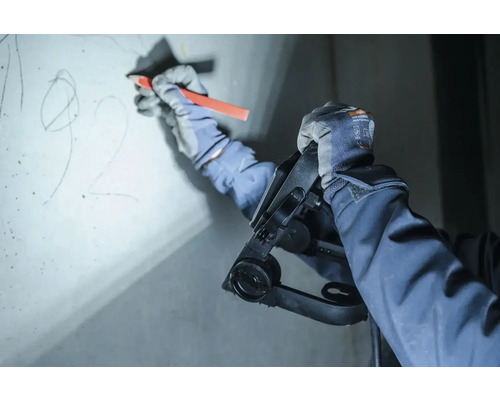 Een persoon gebruikt een passer en een pen om af te tekenen op een muur.