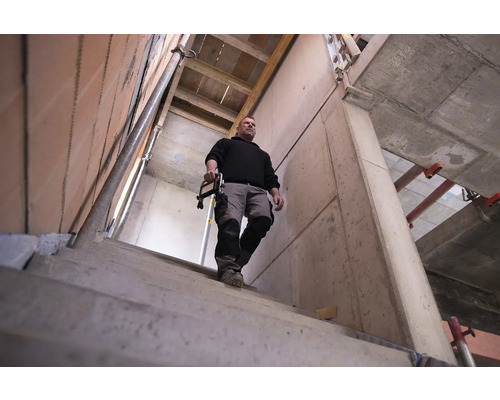 Man met gereedschap op een bouwplaats met metselwerk