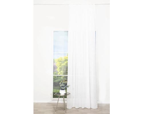 Lichte kamer met raam, wit gordijn en een bijzettafel met decoratie.