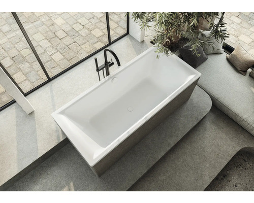 Vrijstaand bad in een lichte badkamer met raam en zithoek